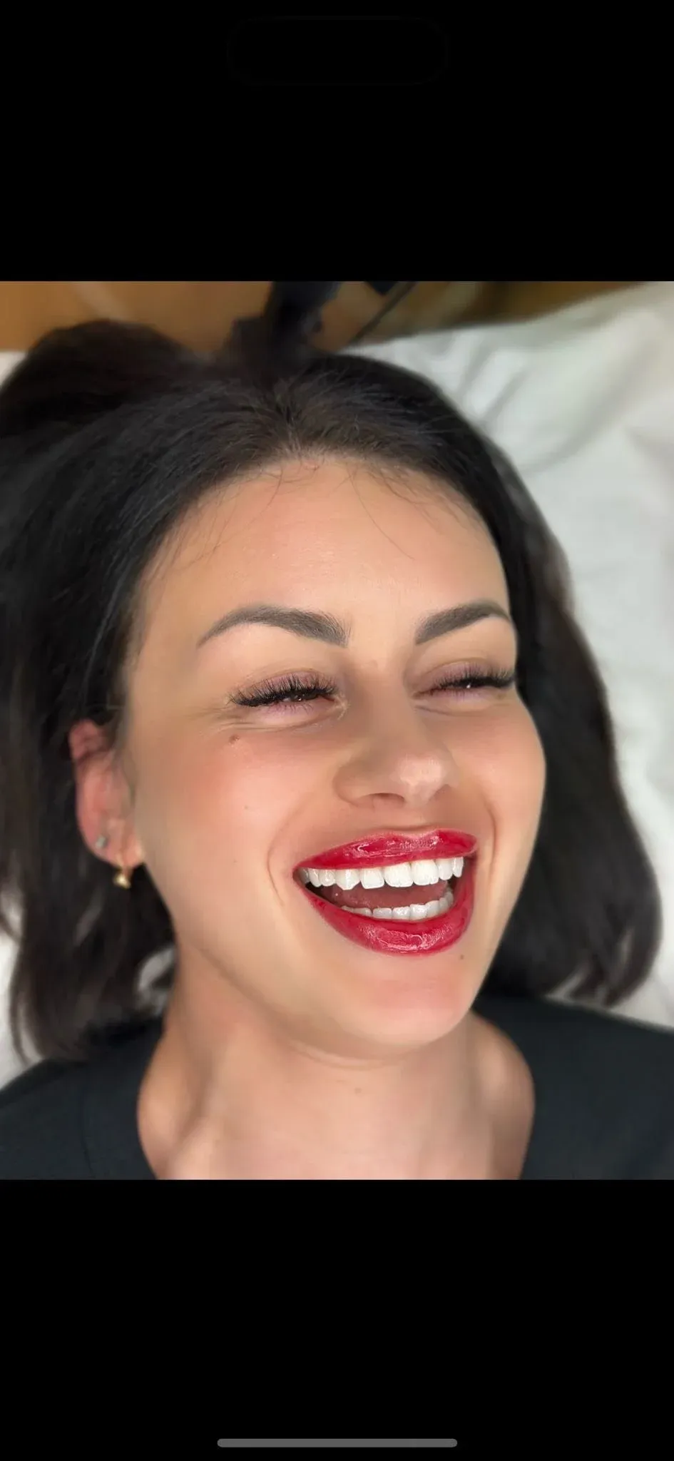 A client smiling, with soft red lip colour
